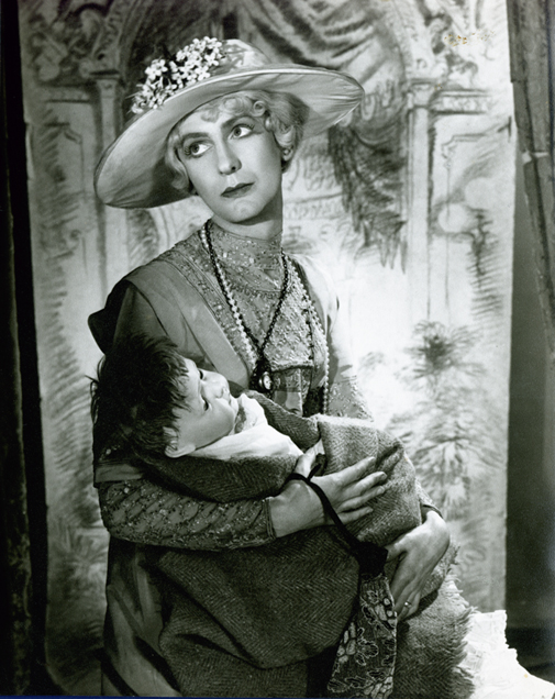 Angus McBean - Man in Drag Holding Baby Doll in Ornate, 19th-Century Setting