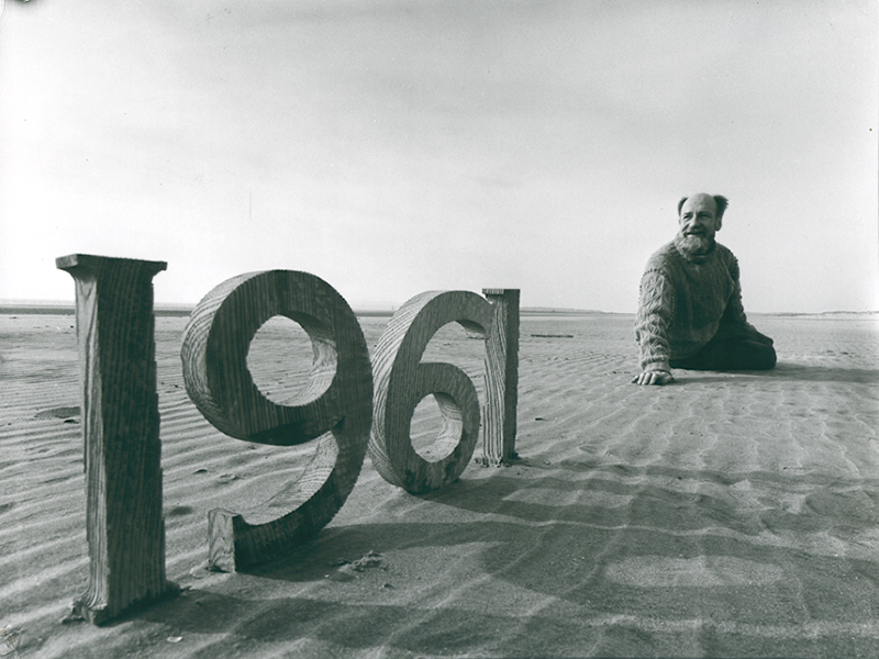 Angus McBean - Christmas Card 1961 - Self Portrait on Beach with Wooden Numbers Angus McBean - Christmas Card 1961 - Self Portrait on Beach with Wooden Numbers