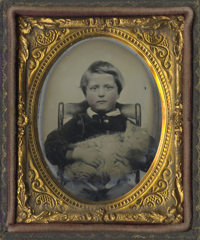 Portrait of a Boy Seated in a Wooden Chair Holding a Cat
